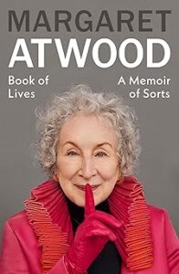 Margaret Atwood, an older woman with short curly gray hair and blue eyes, holding a finger to her mouth as if to say she has a secret. The background is gray and the title is in a white font.