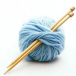 two knitting needles in a light blue ball of wool
