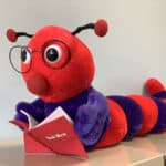 image of a read stuffed toy bookworm with glasses on reading a book.