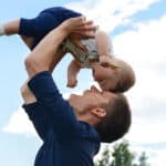 Photo of father lifting his baby over his head