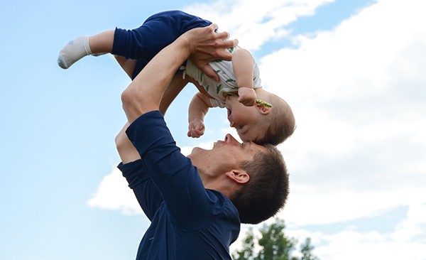 Photo of father lifting his baby over his head