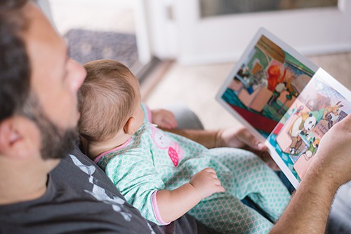 image of man reading to a young child on his lap.