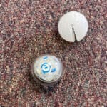 image of ball-shaped Sphero Mini next to its its white rubber cover.