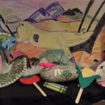 Photo of arts and crafts, including stick puppets, a painted rock and a painting of scenery