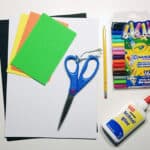 image of craft supplies, including coloured paper, scissors, white glue and Crayons