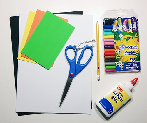 image of craft supplies, including coloured paper, scissors, white glue and Crayons
