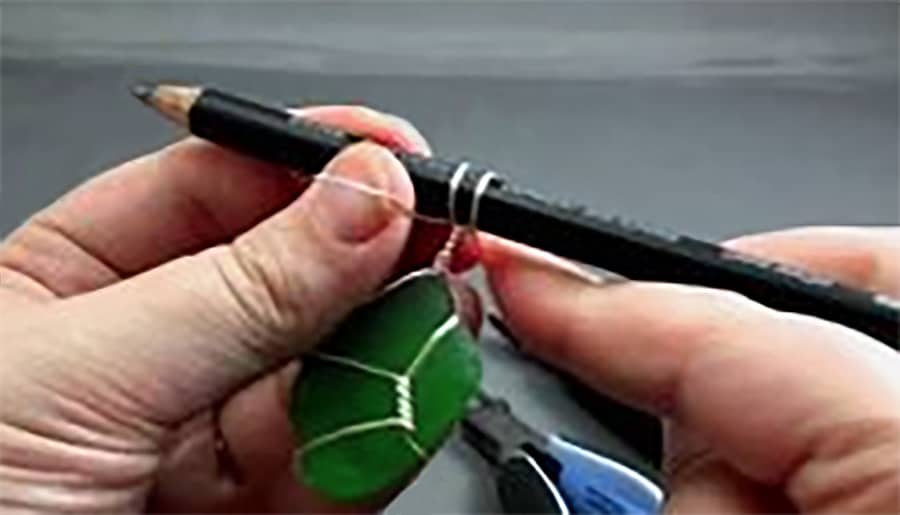 photo of two hands holding a pencil with a wire on it to twist around green beach glass