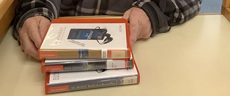 image of a stack of three playaways in orange plastic cases on a desk