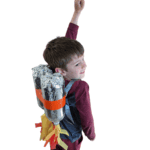Boy wearing a tinfoil jetpack on his back with yellow and orange paper flames coming out of the bottom