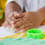 child's hands molding playdough