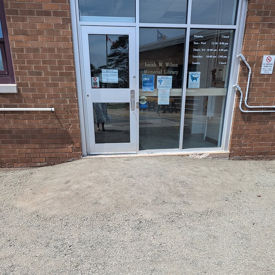 a single library entrance door with windows and a packed gravel mound in front of it.