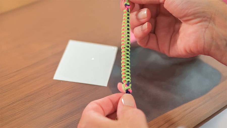 two hands holding a multi-coloured zipper bracelet