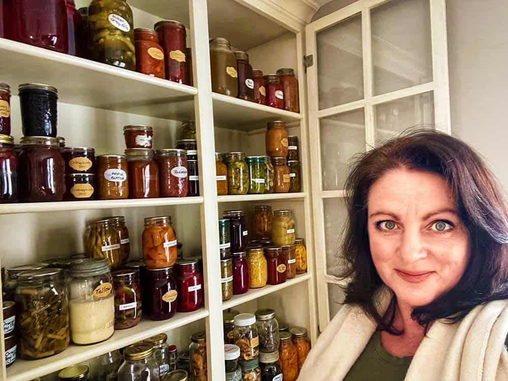 woman next to shelves filled with jars of preserves