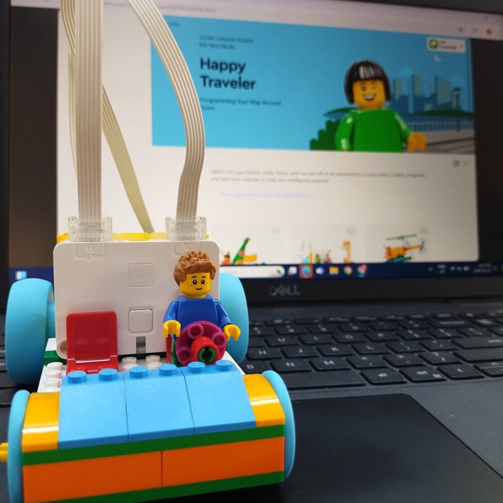 LEGO Spike car with driver in front of a laptop screen.