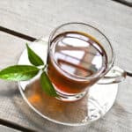 clear glass up of tea with herbal sprig on the side