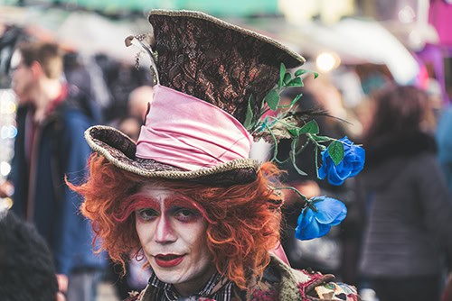 photo of someone dressed as the Mad Hatter with large top had, red hair and bushy eyebrows with a painted white face