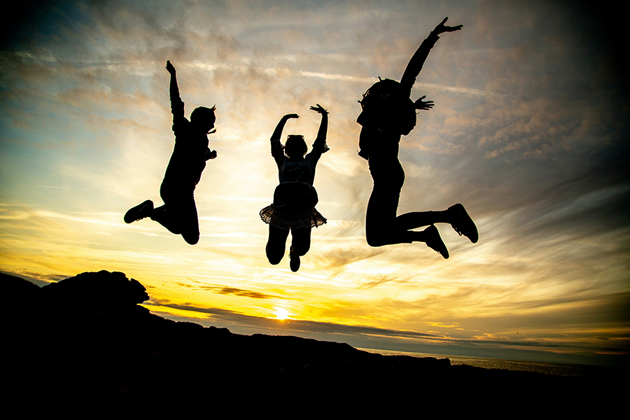 photo of the silhouettes of three children jumping in the air