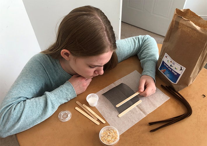 image of a girl placing a wooden stir stick on a brown piece of paper.