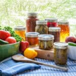 image of jars of canned vegetables and raw vegetables on a table