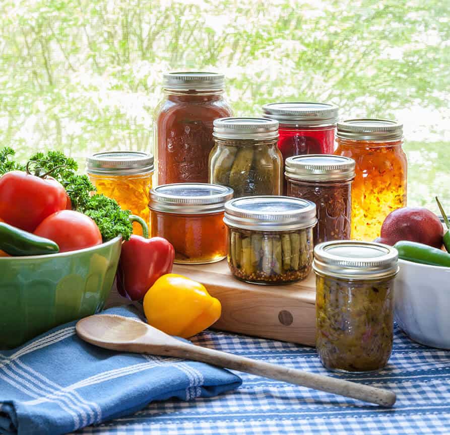 image of jars of canned vegetables and raw vegetables on a table