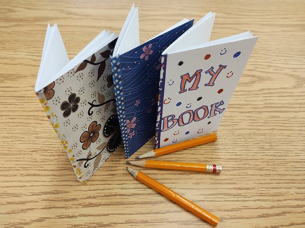 image of three small booklets on a table with three pencils
