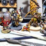 image of painted miniature game pieces on a work bench with paints and tools.