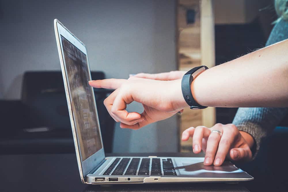 image of two hands working on a laptop computer.