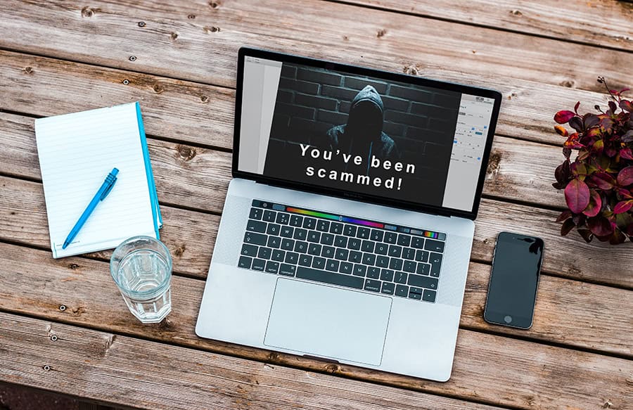 image of a laptop computer on a desk with the text 'You've been scammed'