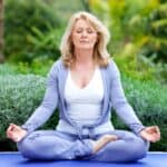 image of a blond womanin a purple track suit seated cross-legged.