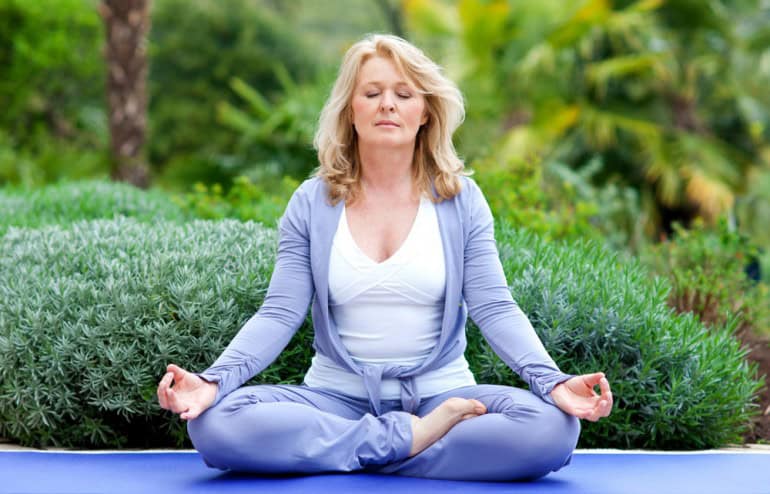 image of a blond womanin a purple track suit seated cross-legged.