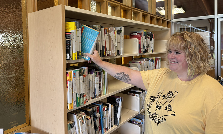image of woman reaching for books on a shelf.