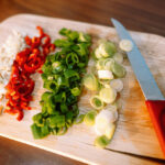 image of chopped vegetables and a knife on a cutting board.