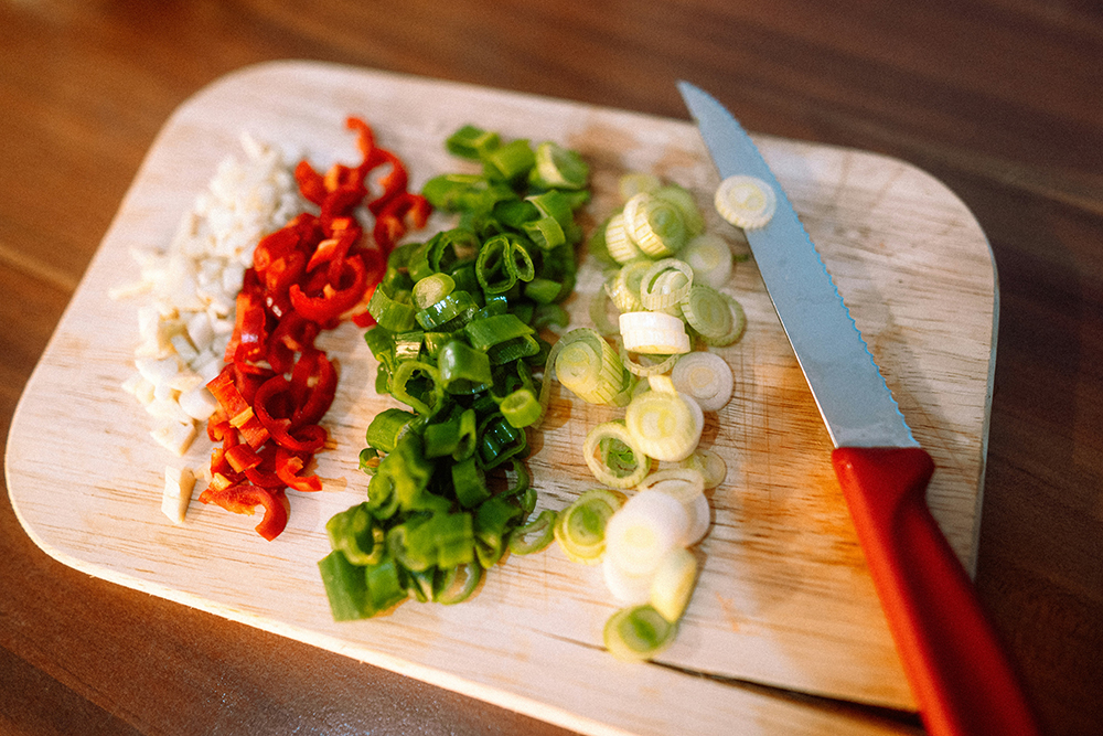 image of chopped vegetables and a knife on a cutting board.