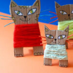 image of three cardboard cats with coloured yarn wrapped around them.