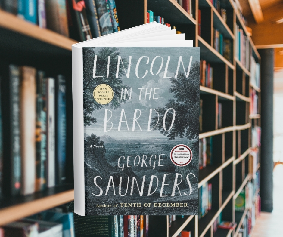 The cover is an illustration in blues and grays of a gloomy forest landscape. Behind the cover are shelves of books.