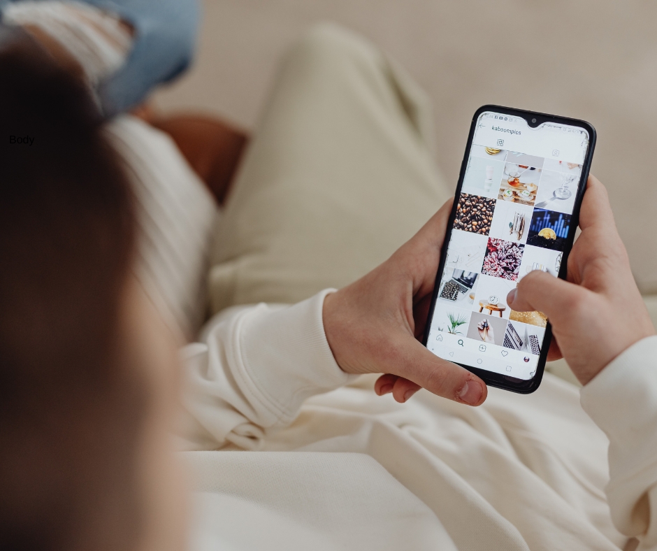 Someone looking at their Instagram photos on their smartphone. The photo is taken directly behind the person.