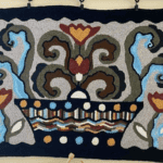 A tapestry that has been rug hooked. It is an interpretation of a pot with flowers and vines growing out of it.