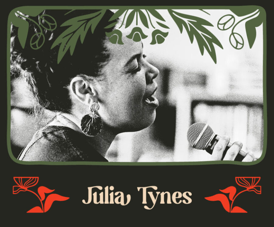 A black and white photo of Julia Tynes. She is a black woman with dark curly hair tied in a bun. She sings passionately into a microphone.