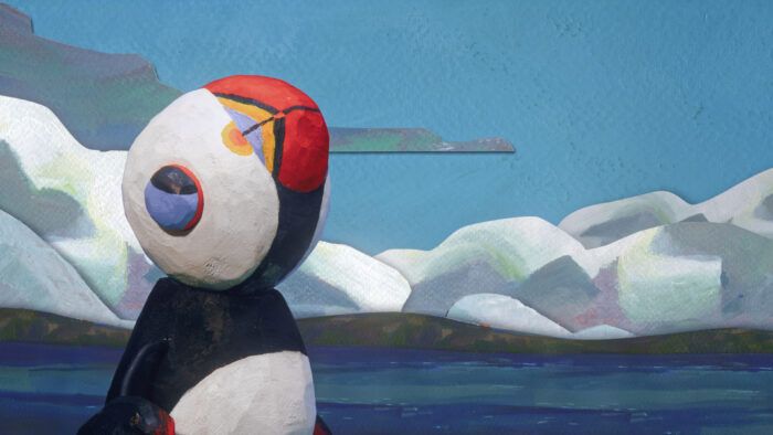 Art titled Get a Grip by Abby Collings. It is of a cartoon puffin looking towards the sky. Around him is the ocean and snow drifts.