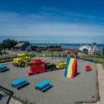 The Meteghan Family Park. The playground has a rock climbing wall, swings, and a wooden train and truck to play in.