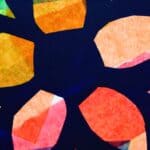 A stained glass window made with coloured tissue paper. It is in the shape of a flower.