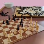 A wooden chessboard and Go board laid out on a table ready to be played.