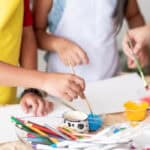 Three children getting ready to paint. They have paint supplies and blank pages.