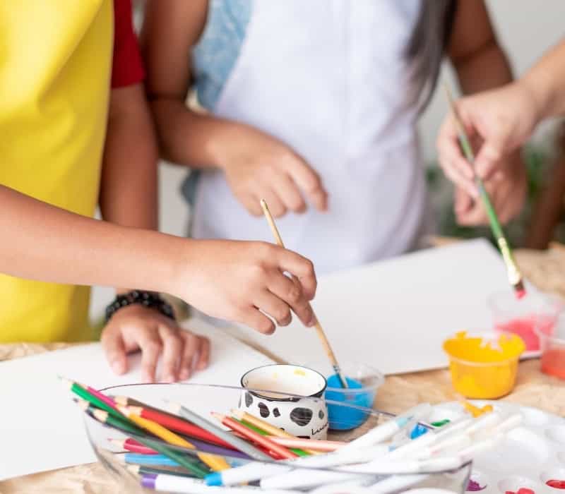 Three children getting ready to paint. They have paint supplies and blank pages.
