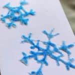 Two blue snowflakes on a card made from glue and salt.
