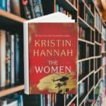 The cover is red and has a blacked out helicopter in the bottom right corner. Behind the cover are shelves of books.