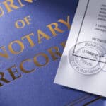 A blue notary record folder. In front of it is a notarized document.